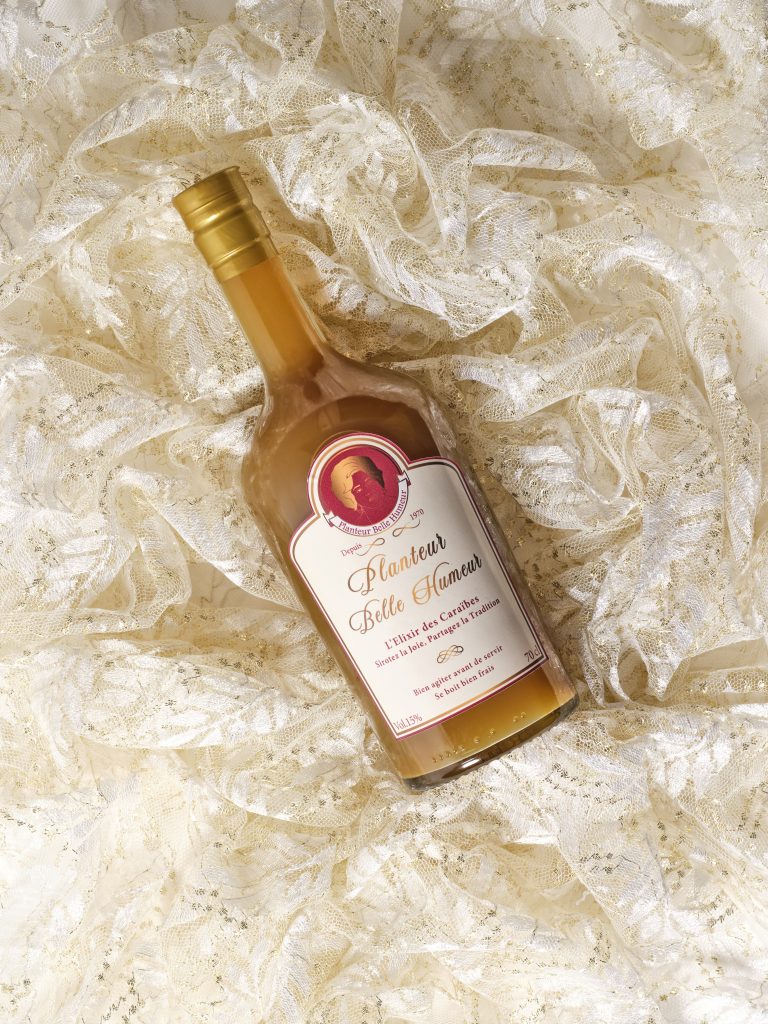 Bouteille de Planteur Belle Humeur posée sur de la dentelle